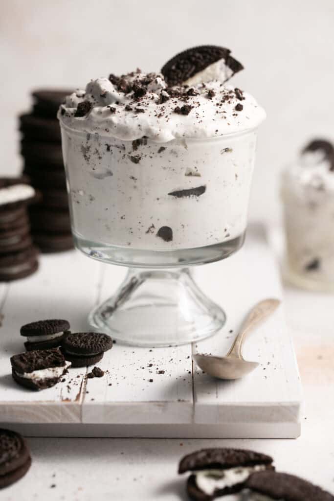 Oreo cream fluff in a small bowl garnished with addtional oreos on the side.