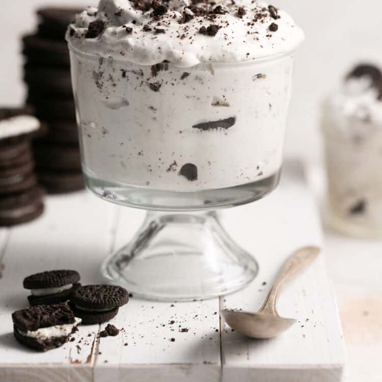 Oreo cream fluff in a small bowl garnished with addtional oreos on the side.