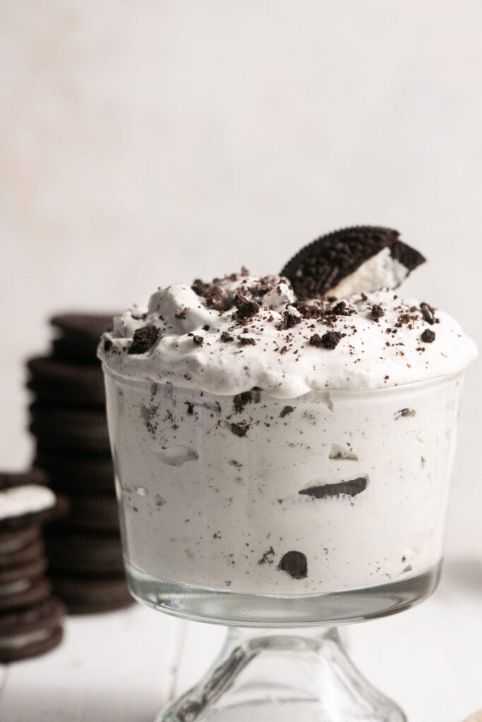 Oreo cream fluff in a small bowl garnished with addtional oreos on the side.