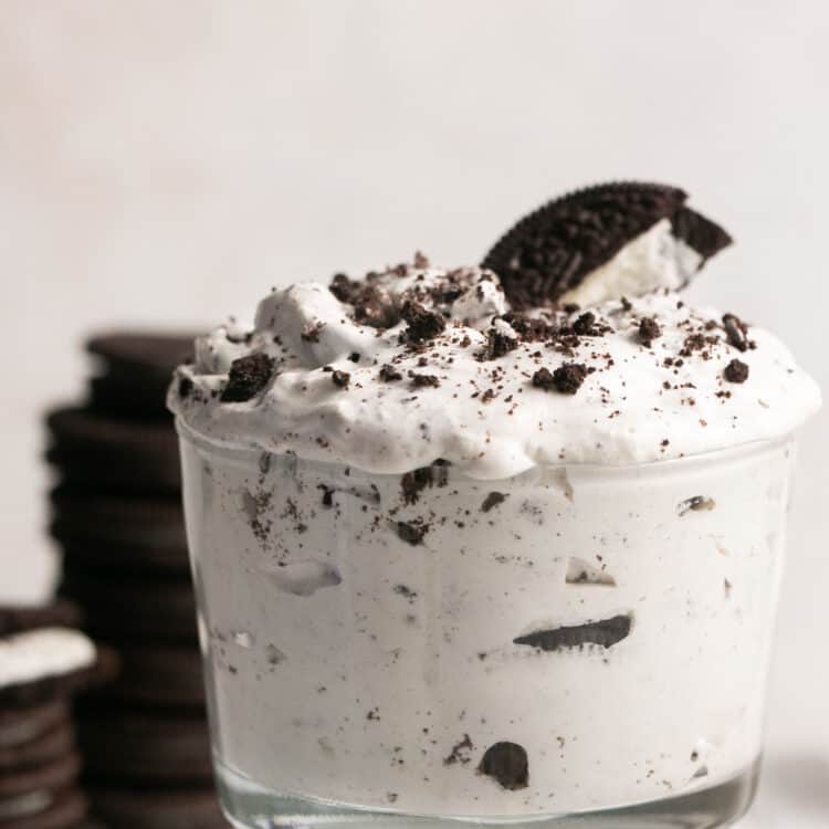 Oreo cream fluff in a small bowl garnished with addtional oreos on the side.