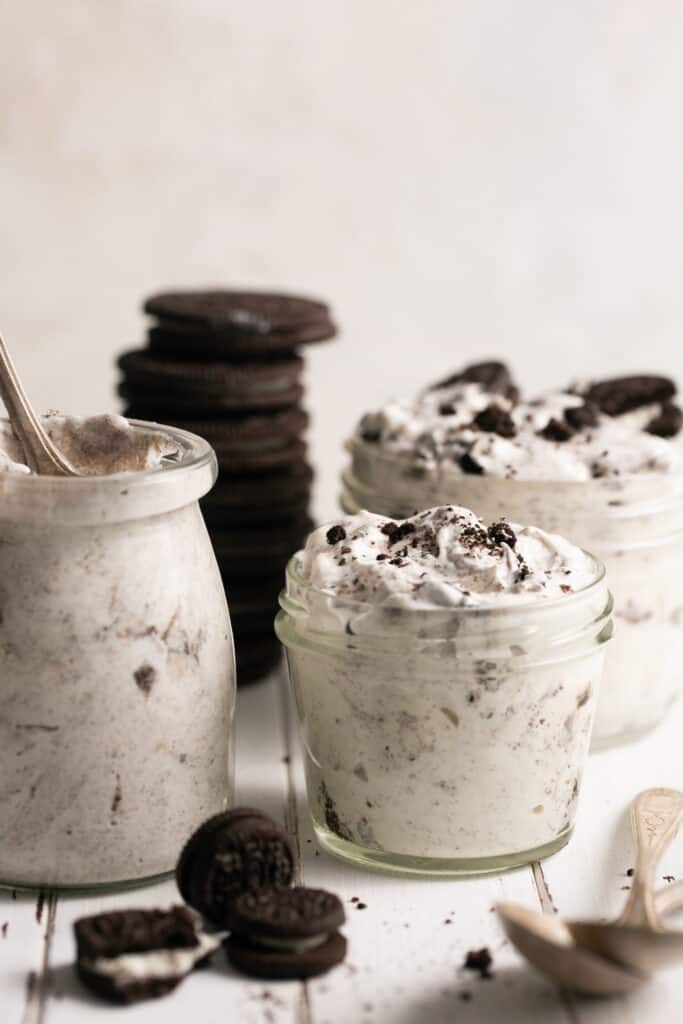 Oreo cream fluff in small jars garnished with addtional oreos on the side.