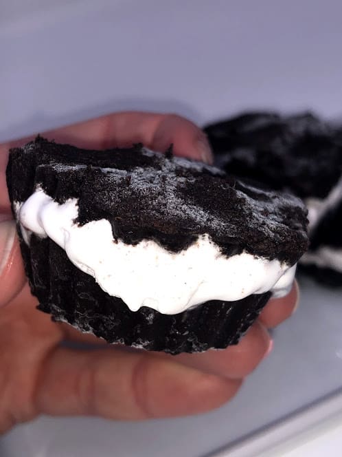 A hand holding an oreo freeze cup with more oreo freeze cups in the background on a plate.
