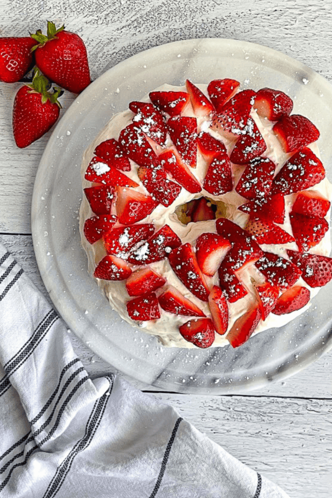 Healthy protein angel food cake topped with strawberries on a plate.