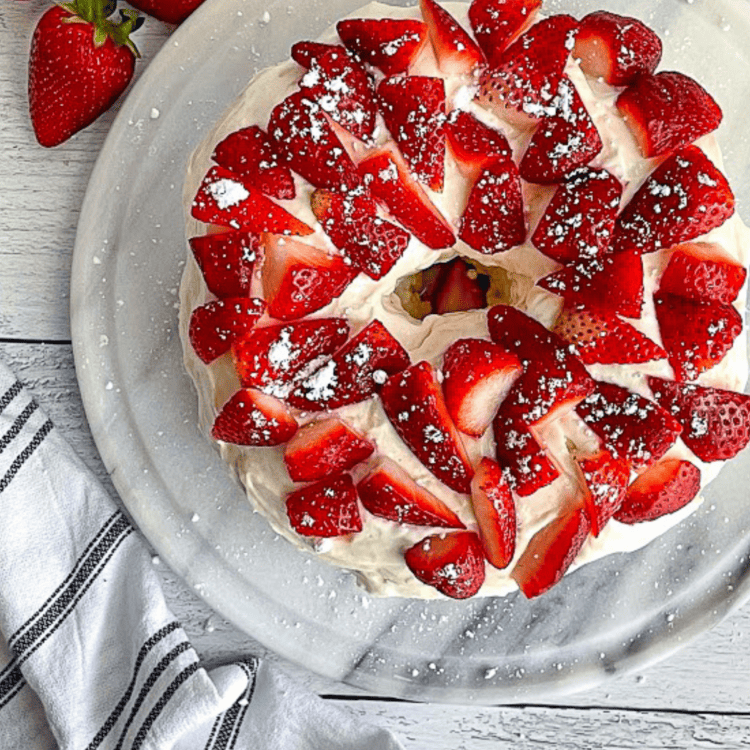 Healthy protein angel food cake topped with strawberries on a plate.