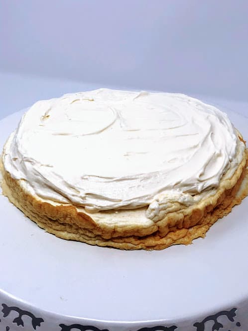Healthy protein angel food cake topped with frosting on a plate.