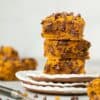 Healthy pumpkin chocolate chip blondies stacked on top of each other on a small plate.