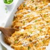 Buffalo chicken, spaghetti squash, and cheese baked in a casserole dish topped with green onions and dressing