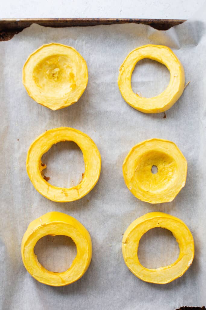 Squash cut into thick rings on a baking sheet with parchment paper.