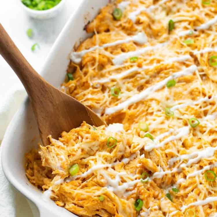 Buffalo chicken, spaghetti squash, and cheese baked in a casserole dish topped with green onions and dressing