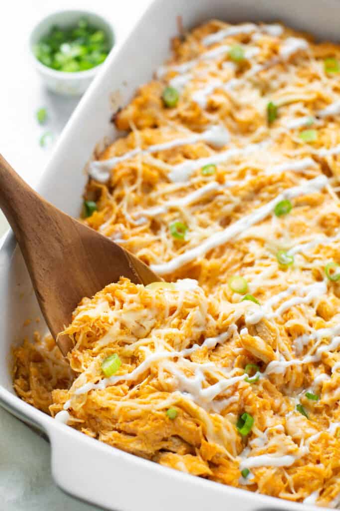 Buffalo chicken, spaghetti squash, and cheese baked in a casserole dish topped with green onions and dressing.