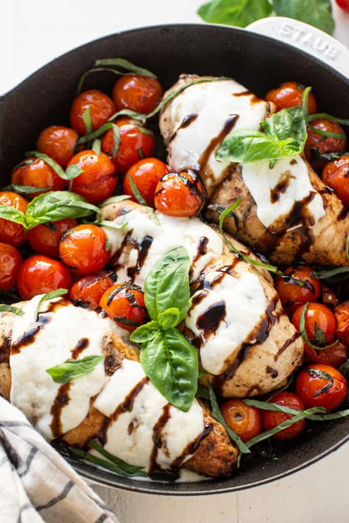 Macro Friendly One Pan Caprese Chicken in a skillet with fresh basil. 
