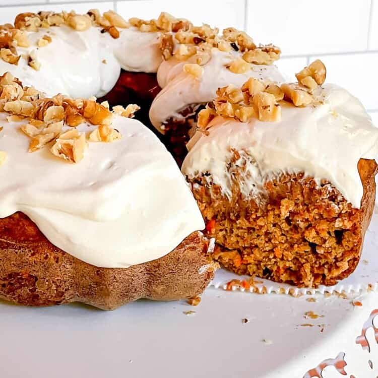 Healthy carrot cake topped with cream cheese frosting on a plate.