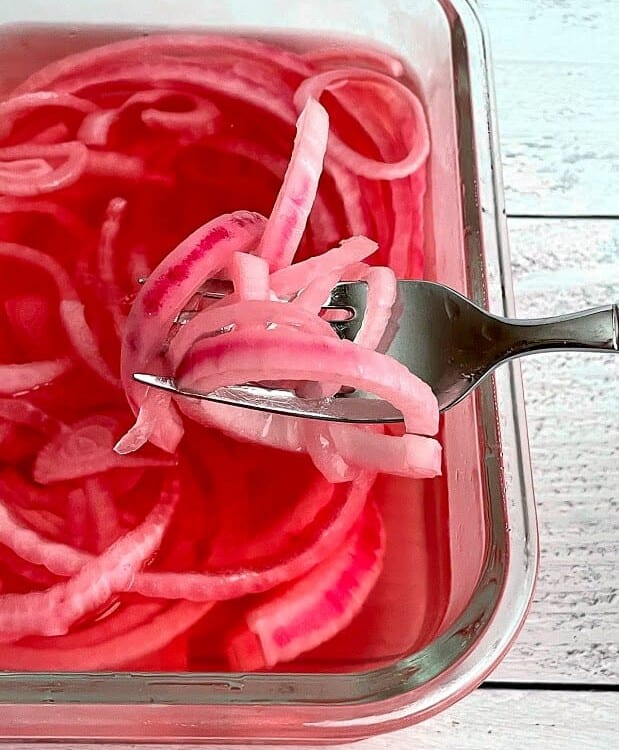 Forkful of cold pickled red onions in a tupperware container