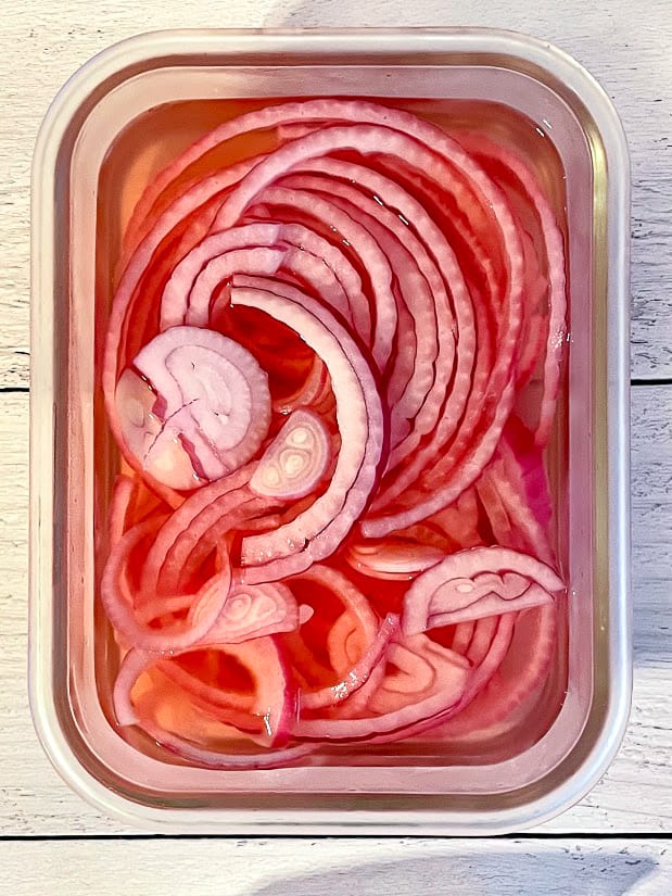 overhead shot of pickled red onions in a tupperware container