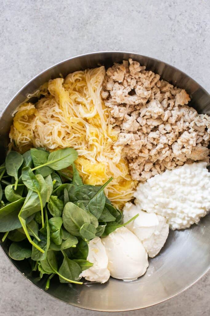 Ingredients for Spinach and artichoke spaghetti squash bake in a large bowl before being mixed together.