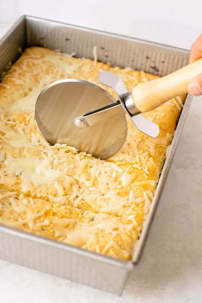 Upside down egg white pizza in a baking dish being cut with a pizza cutter.