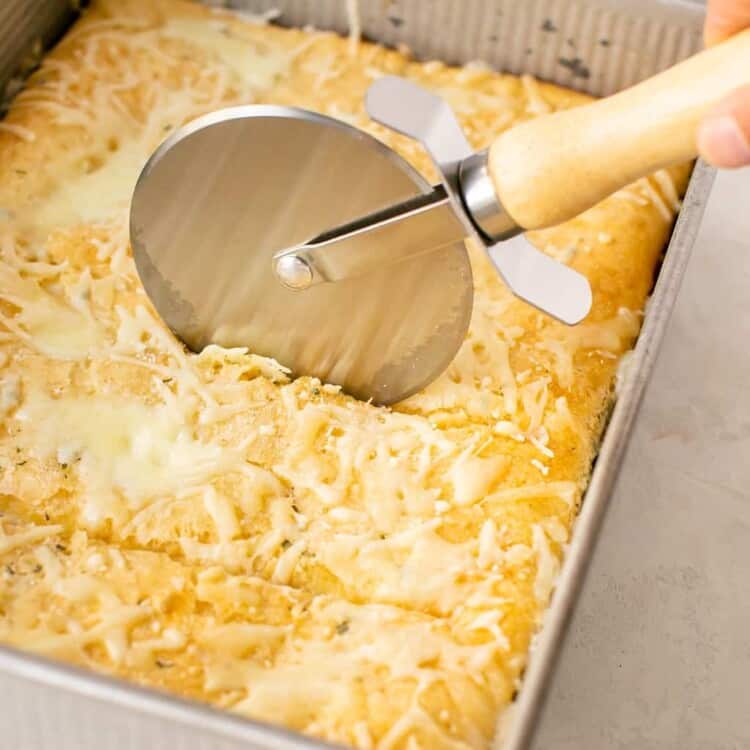 Upside down egg white pizza in a baking dish being cut with a pizza cutter.