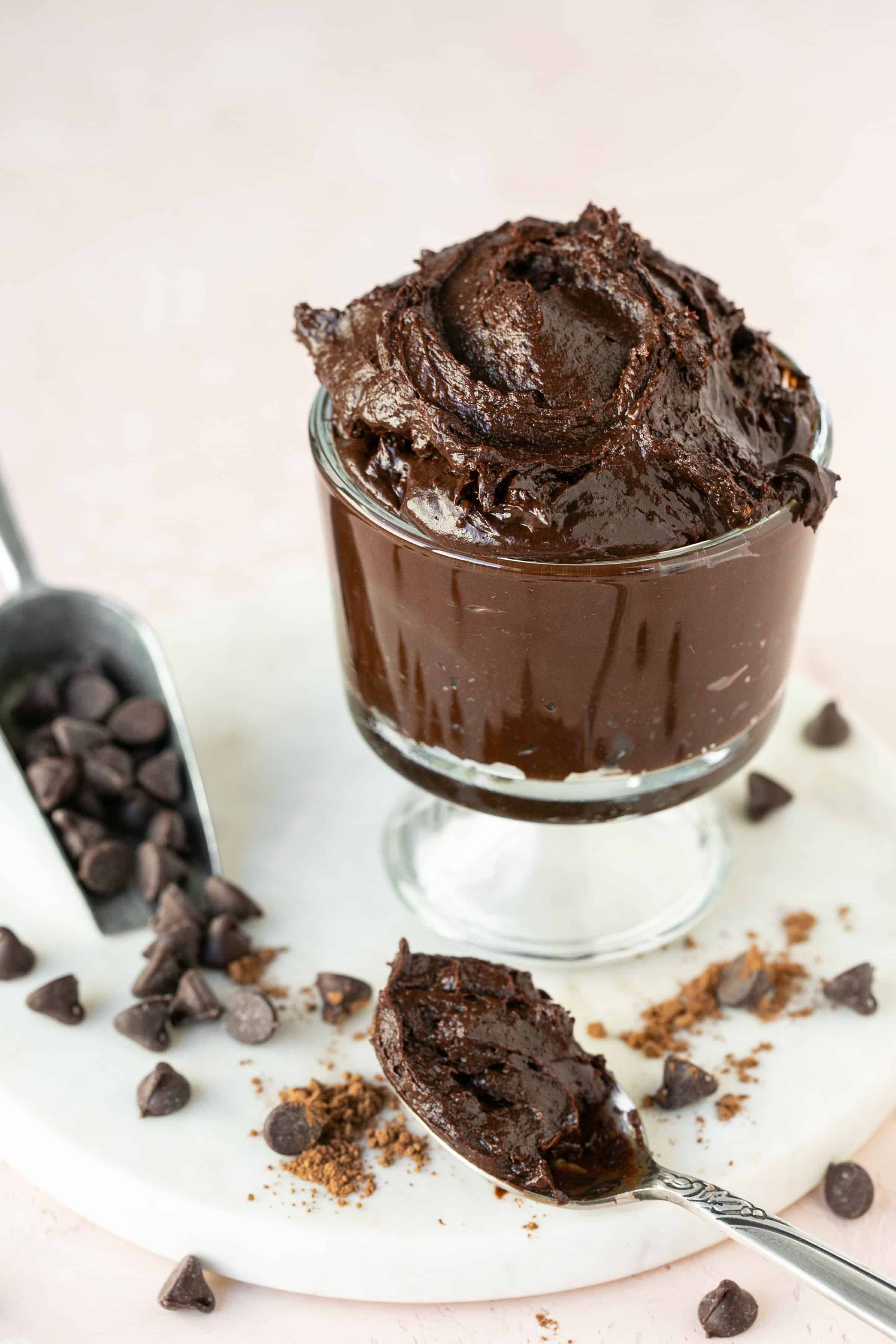 Healthy brownie batter in a small bowl with a spoon and chocolate chips on the side.