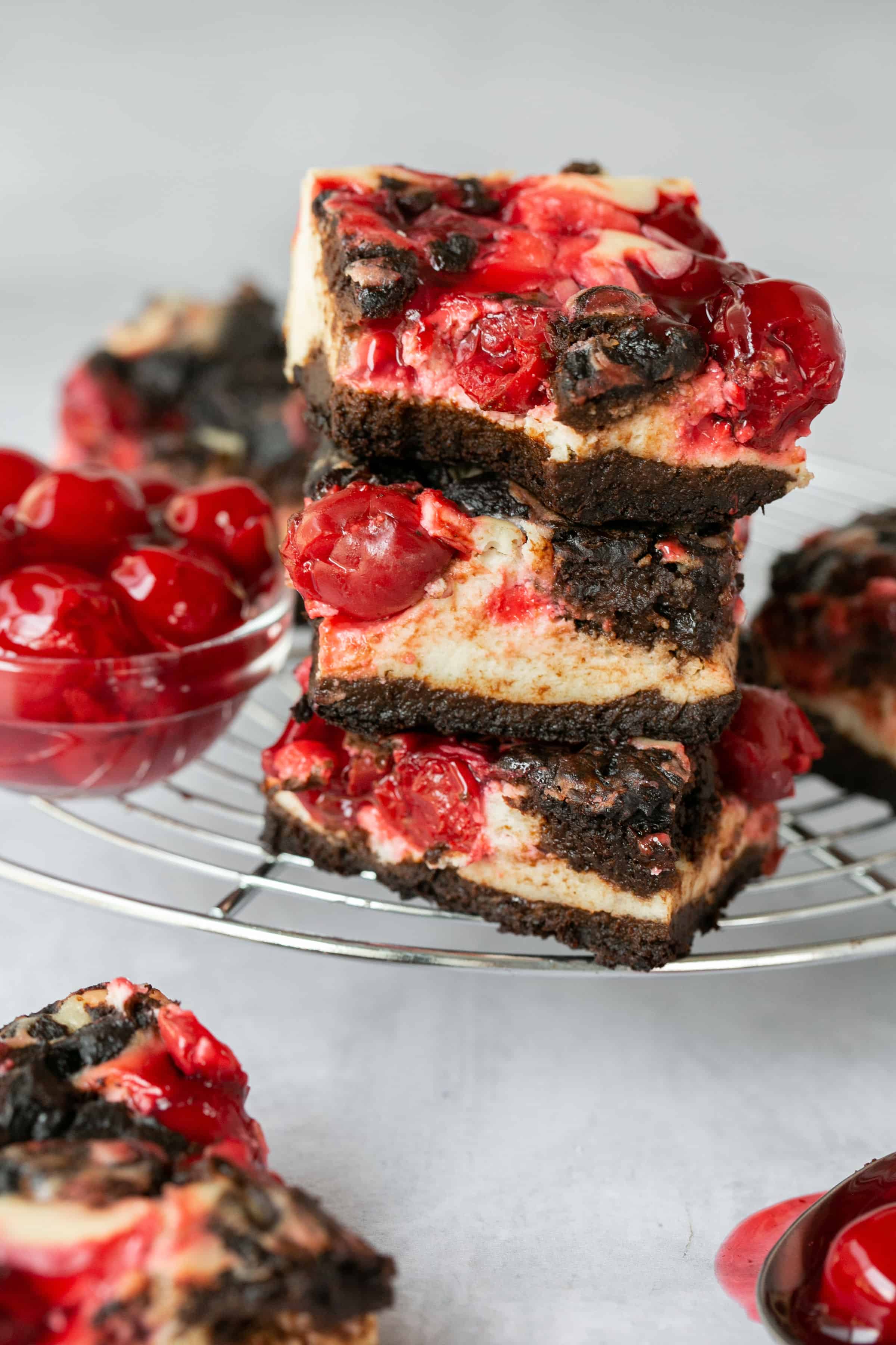 Cherry cheesecake brownies on a cooling rack, some stacked on top of each other.
