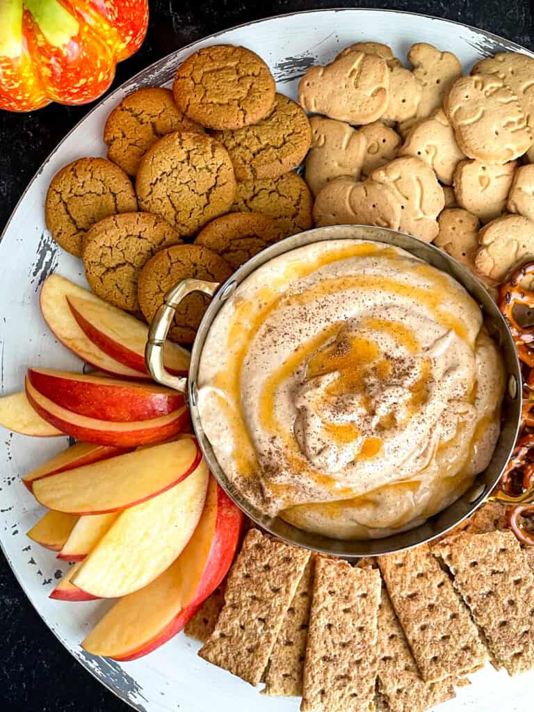 Skinny pumpkin dip on a tray with apple slices, graham crackers, pretzels, animal crackers, and cookies.