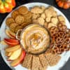 Skinny pumpkin pie dip on a tray with apple slices, graham crackers, pretzels, animal crackers, and cookies.