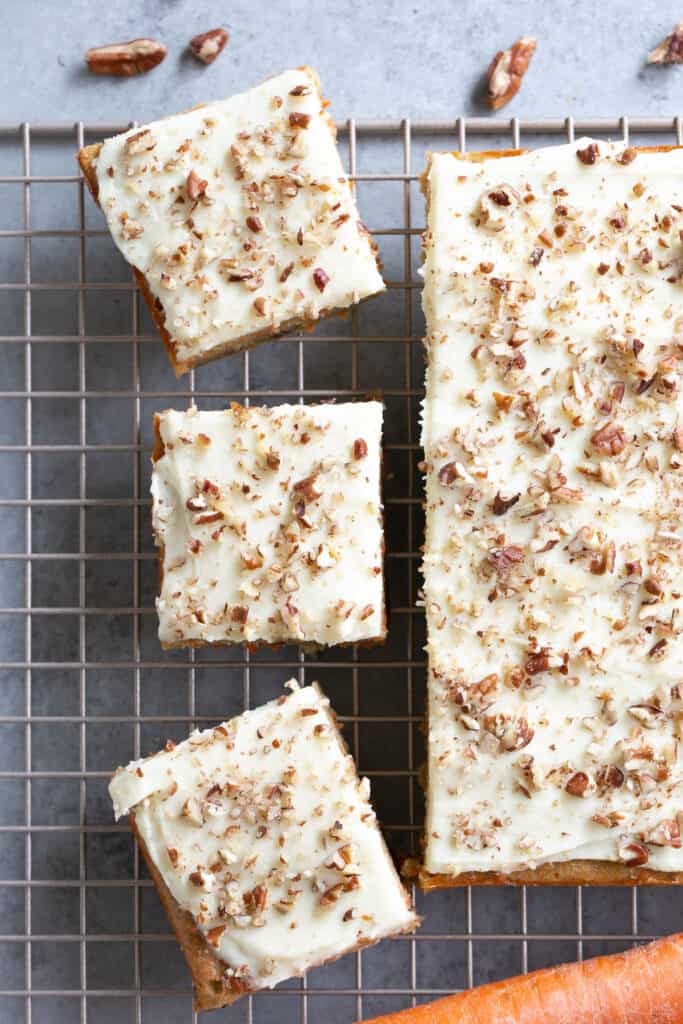 Healthy carrot cake blondies, some cut into bars, on a cooling rack.