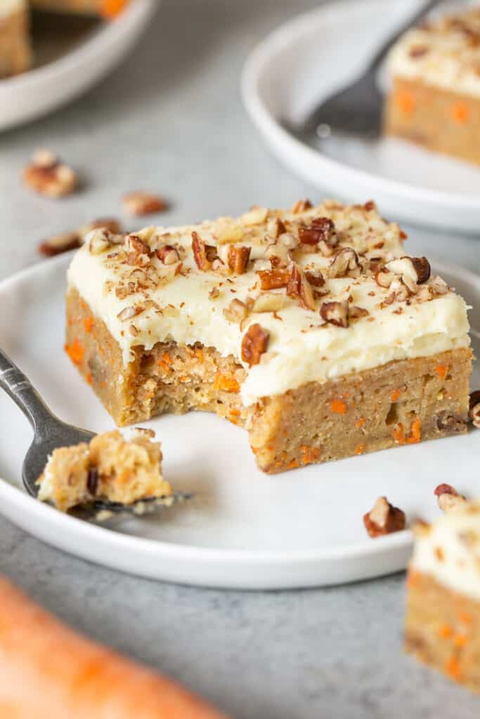 A healthy carrot cake blondie on a small plate with a fork.
