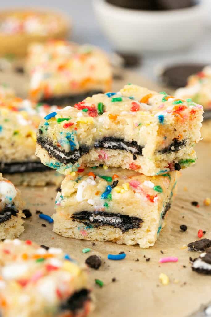 Two Cake Batter Oreo Blondies stacked on top of each other with a bite taken out of the top one