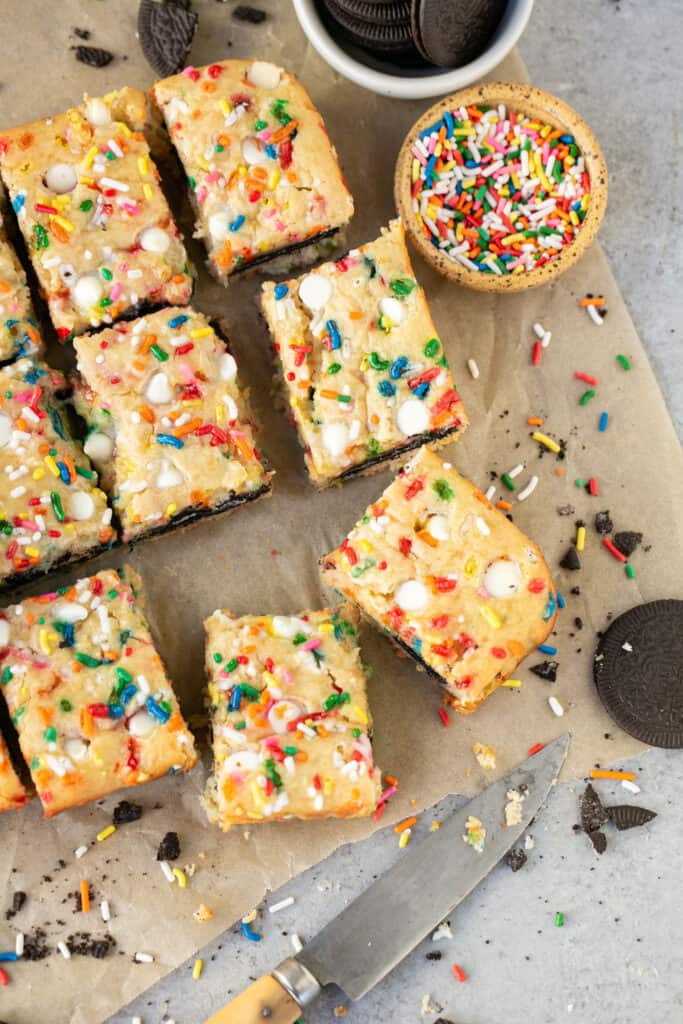 12 Cake Batter Oreo Blondies on parchment paper.