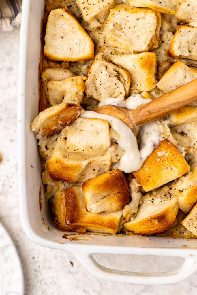 Biscuits and gravy casserole in a casserole dish with a wooden spoon