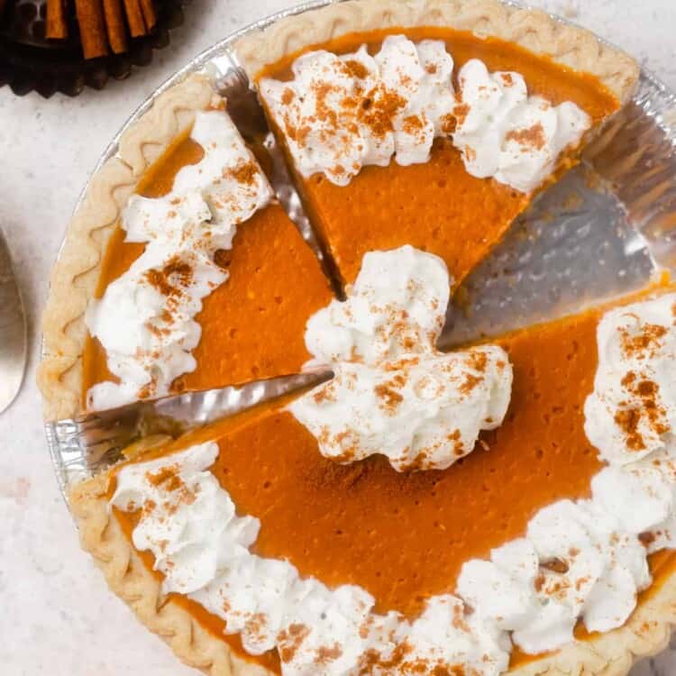 Low calorie pumpkin pie sliced in a pie pan with whipped cream.