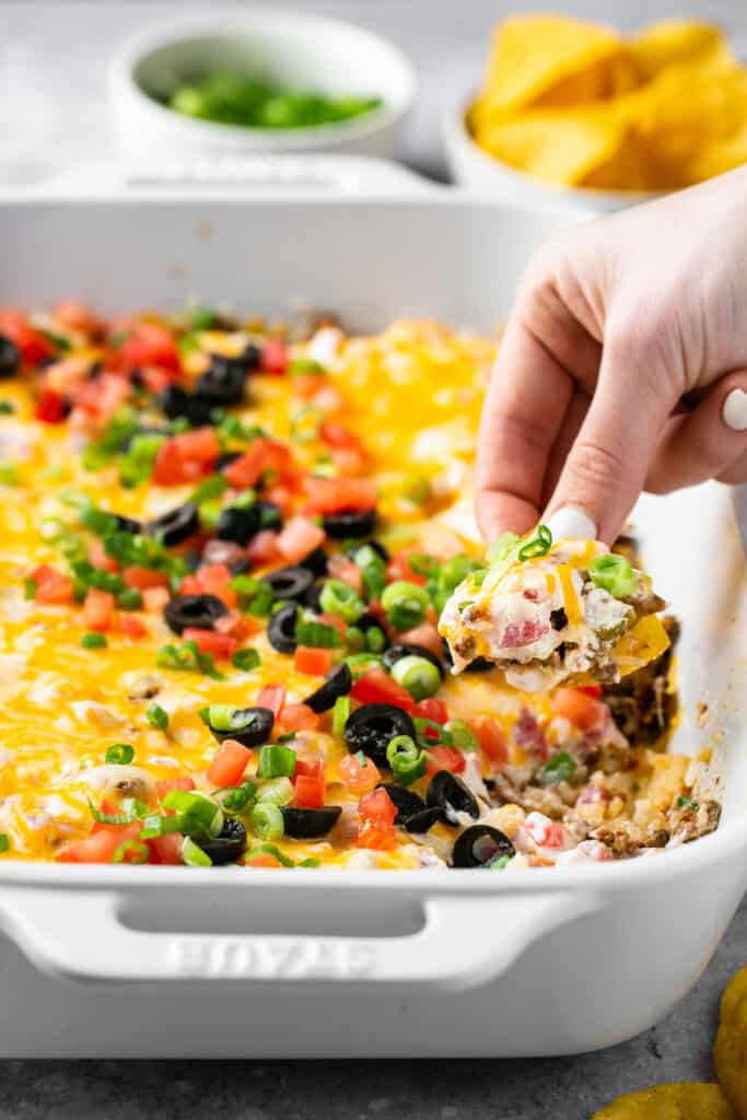 Mexican Cauliflower Rice Dip in a baking dish with a chip being dipped in it.