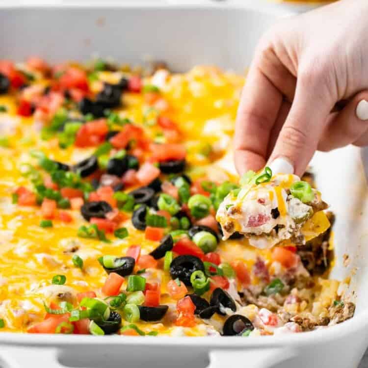 Mexican Cauliflower Rice Dip in a baking dish with a chip being dipped in it.