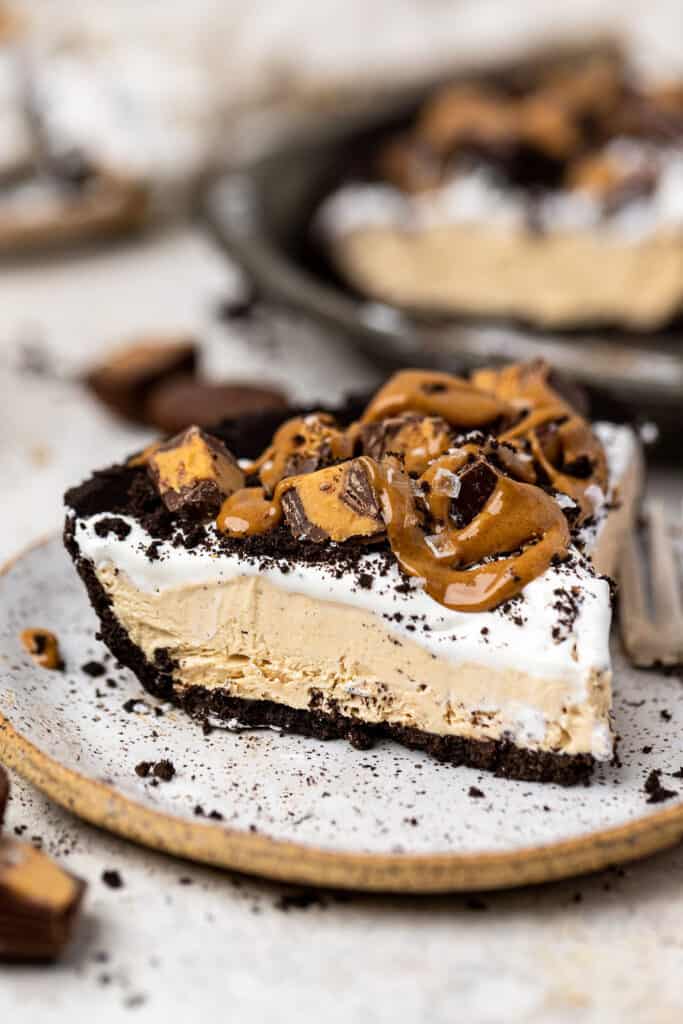 No bake oreo peanut butter pie topped with chopped Reese's on a small plate.