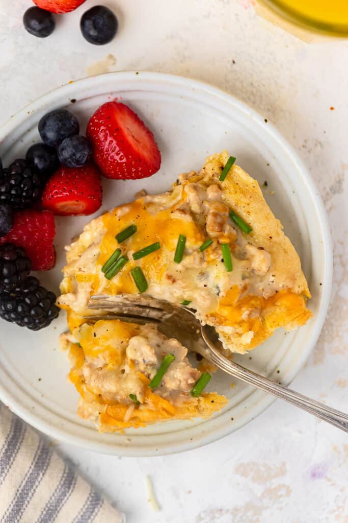 Healthy sausage and gravy breakfast casserole on a plate with berries and a fork.