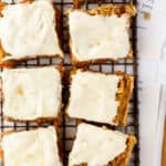 Carrot cake oatmeal bake topped with vanilla maple cream cheese icing cut into squares on a cooling rack.