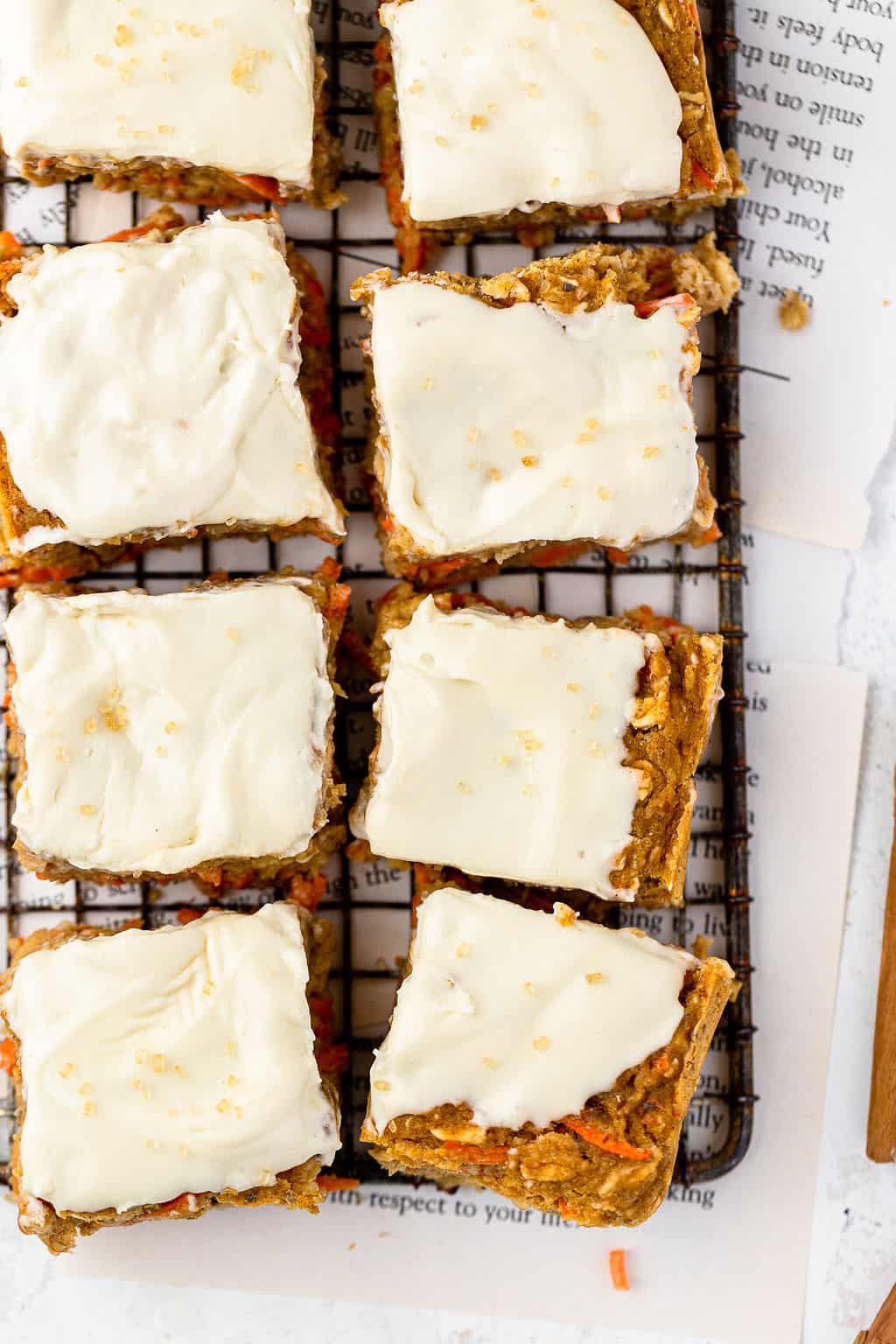 Carrot cake oatmeal bake topped with vanilla maple cream cheese icing cut into squares on a cooling rack.