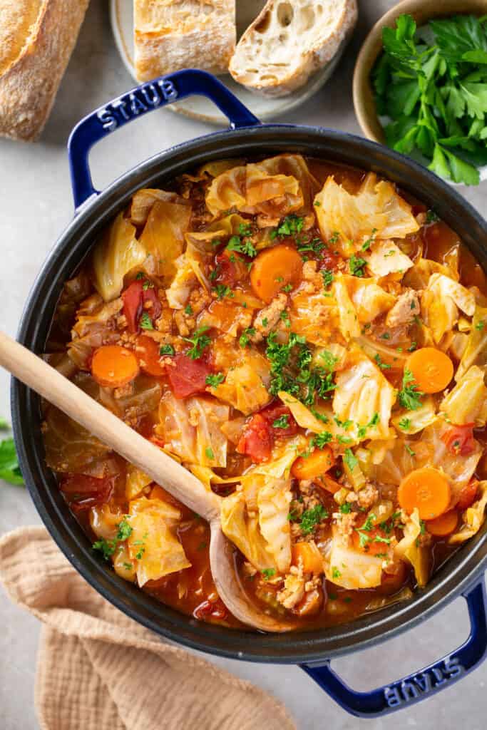 Italian Chicken Cabbage Soup in a pot with a wooden spoon