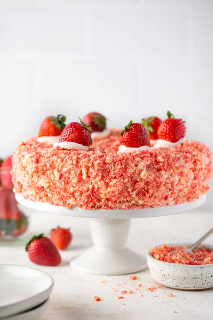 Strawberry crunch cake topped with straberries on a cake stand.