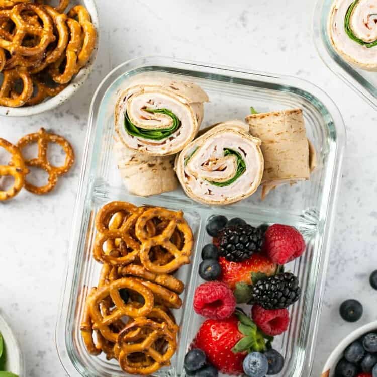 Meal prep pinwheels in a meal prep container with prezels and berries.