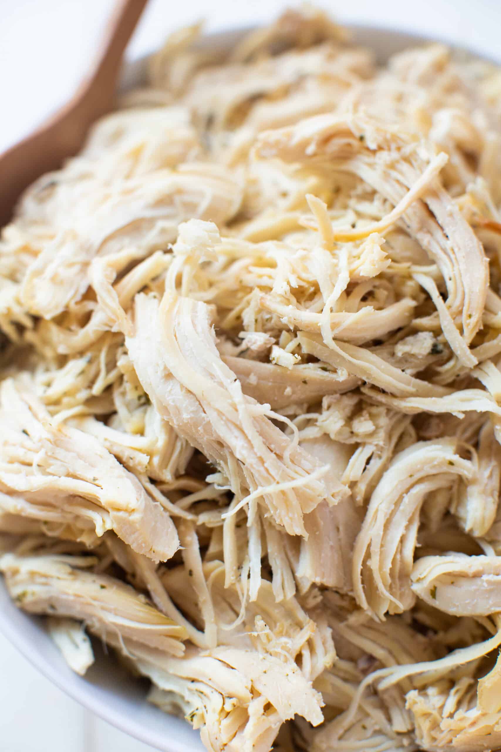 Zoomed in view of shredded chicken in a bowl.