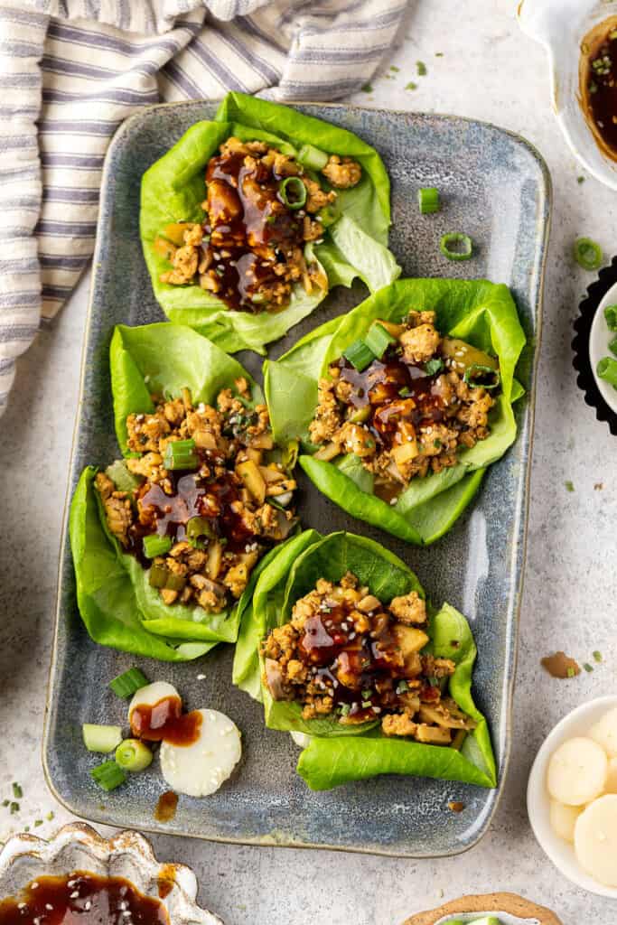 Chicken lettuce wraps served on a serving plate garnished with green onion