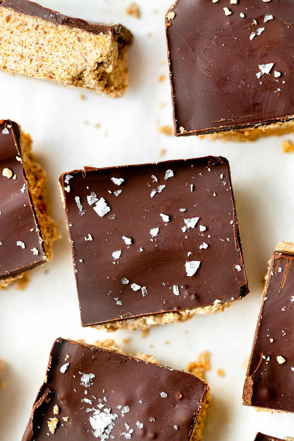 Chocolate cookie dough squares topped with flakes of sea salt on parchment paper.
