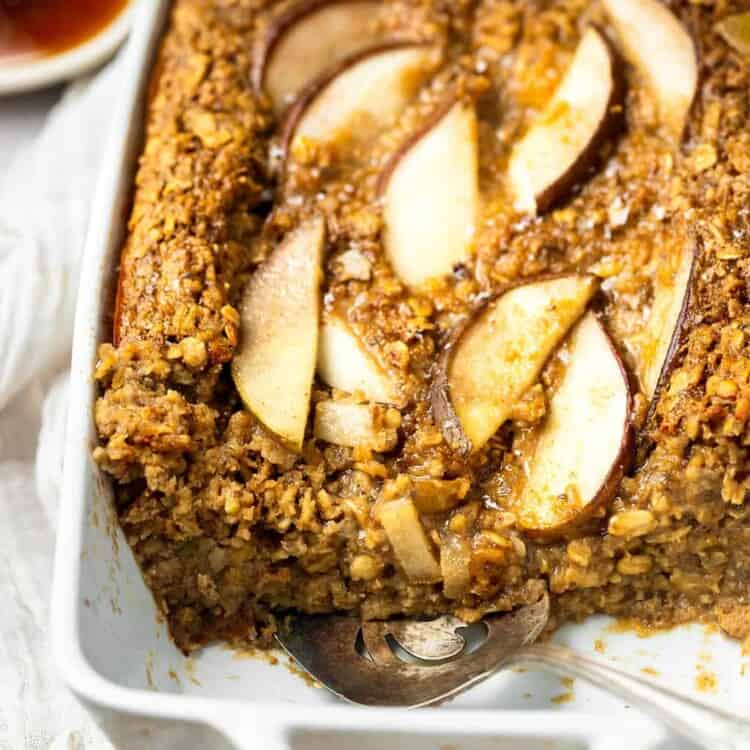 Spiced pear oatmal in a baking dish topped with sliced pears.