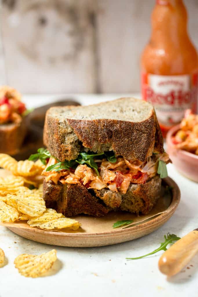 Healthy buffalo chicken salad sandwich on a plate with a side of chips.