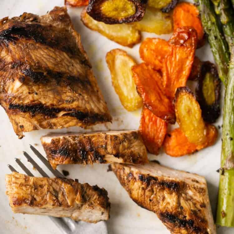 Balsamic chicken with a side of veggies on a plate with a fork.
