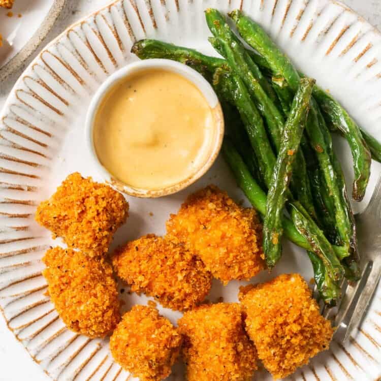Panko baked chicken nuggets on a plate with a side of green beans and honey mustard.