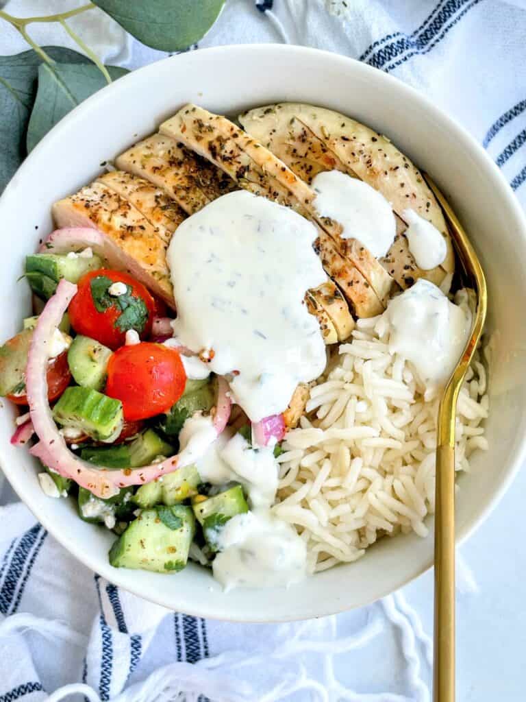 Greek Chicken Bowl with a fork topped with tzatziki