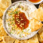 Whipped feta with honey in a bowl with pita chip on the side.