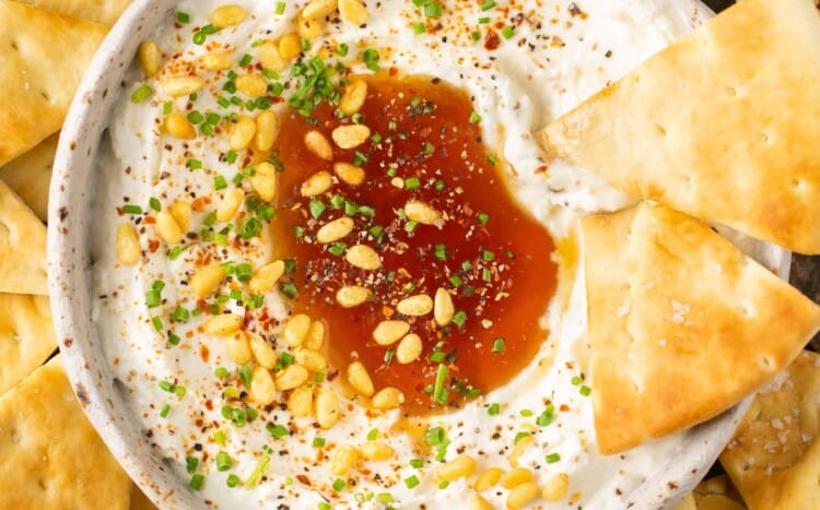 Whipped feta with honey in a bowl with pita chip on the side.